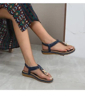 Close-up of navy T-strap sandals with woven leather and golden horseshoe buckle detail