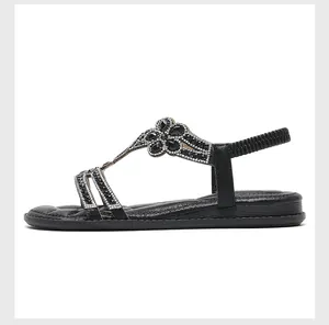 Detail view of black flat sandals with sparkling rhinestone flowers and elastic heel strap