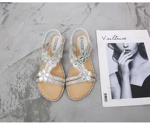 Vue détaillée de sandales bohèmes avec strass et fleurs en perles sur fond en marbre