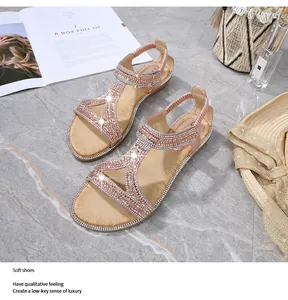 Dettaglio di sandali rosa con strass, cinturino a T e fascia elastica su fondo marmo