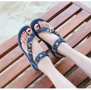 Sandali bassi bohémien blu scuro con strass e perline di legno su sfondo di legno naturale