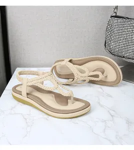 Détail de sandales tressées beige avec bride arrière élastique sur fond marbre