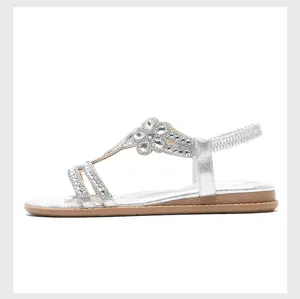 Macro shot of silver rhinestone floral clusters and t-strap detail on flat summer sandals