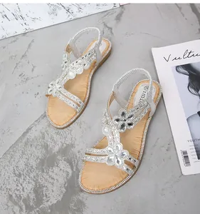 Gros plan de sandales argentées avec strass en forme de fleur et bride élastique confort