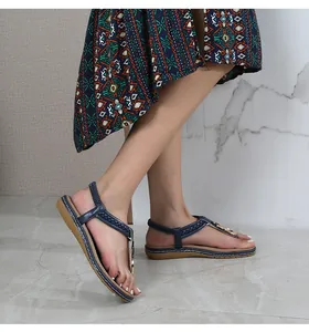 Detail of navy thong sandals featuring woven texture and gold circular metal hardware