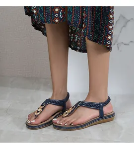 Detailed view of woven blue T-strap sandals with elegant gold buckle and flat sole