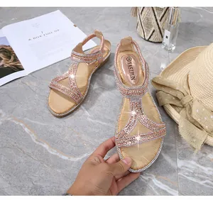 Dettaglio di sandali con cinturino a T oro rosa e strass lucidi su fondo marmo