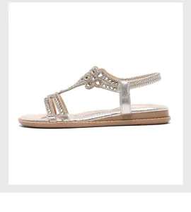 Detail of champagne gold flat sandal with T-strap flower rhinestone decoration and elastic back