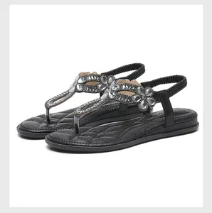 Detailansicht schwarzer flacher Sandalen mit Strasssteinen und elastischem Fersenriemen