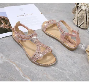 Dettagli macro dei sandali piatti bohémien oro rosa con fitte decorazioni in strass