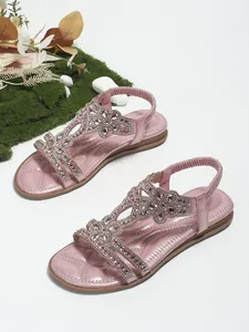 Detail view of pink rhinestone flat sandals with floral patterns and elastic heel straps