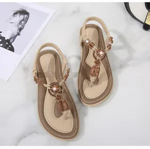 Detail of bohemian flat sandals with woven floral patterns and wooden beads decorations