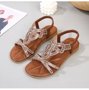 Detail of brown flat sandals with rhinestone straps and elastic back on fashion background