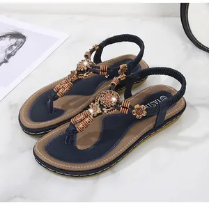 Detail of bohemian flat sandals with wooden beads and rhinestone flower decorations
