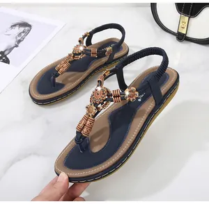 Detail of navy blue flip flops with ethnic beads and crystal flower on white marble