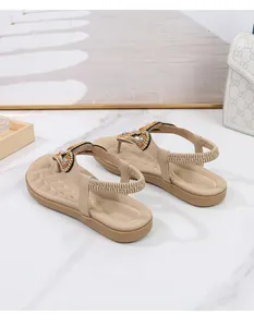 Λεπτομέρεια από μπεζ boho φλατ σανδάλια με στρας και ελαστικό λουράκι στη φτέρνα