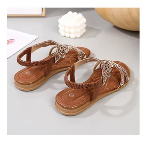 Detail of brown flat sandals with sparkling rhinestone straps and elastic heel