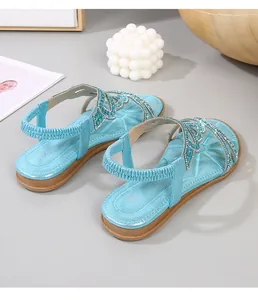 Detailed view of blue glitter flat sandals with butterfly rhinestone patterns and elastic heel