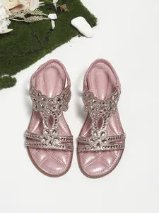 Macro detail of pink glitter flat sandals with intricate rhinestone floral embellishments