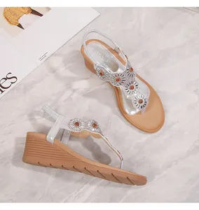 Dettaglio di sandali con zeppa bohémien argento con fiori di strass e cinturino a T