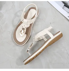 Detail view of beige thong sandals featuring gold buckles and elastic heel straps
