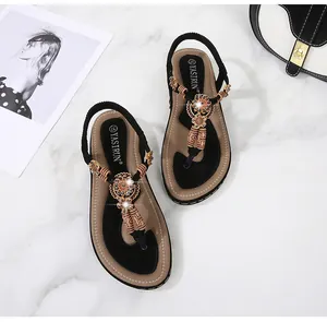 Detail of bohemian flat sandals with ethnic beads, floral accents and elastic heel strap