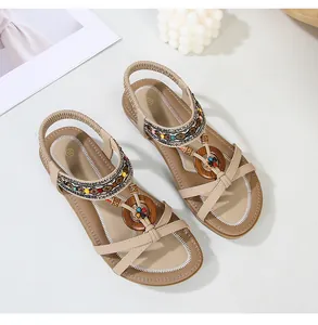 Detail of bohemian flat sandals featuring colorful bead charms and woven elastic straps