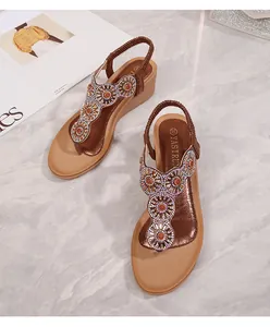 Dettaglio di sandali con zeppa boho marroni con perline a girasole e cinturino elastico
