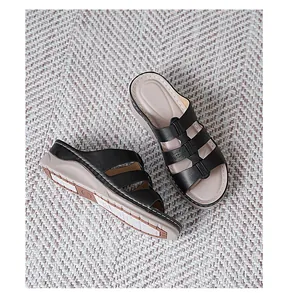 Detailweergave van zwarte sleehaksandalen met drie bandjes en stiksels op de beige zool