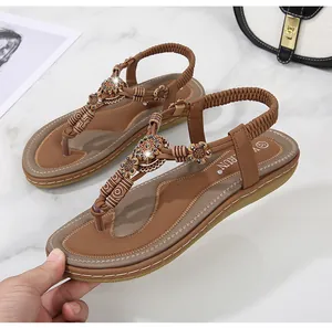 Detail of bohemian flat sandals with brown beadwork and floral patterns on marble
