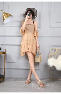 Dettaglio di sandali bassi boho con strass abbinati a un abito in chiffon beige a balze