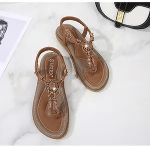 Detail of bohemian summer sandals with intricate flower beads and T-strap on marble