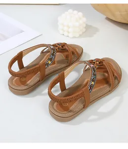 Detailed view of brown flat sandals with colorful beaded straps and elastic back