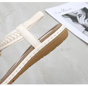 Close-up of woven straps and elastic back strap on cream flat sandals for women