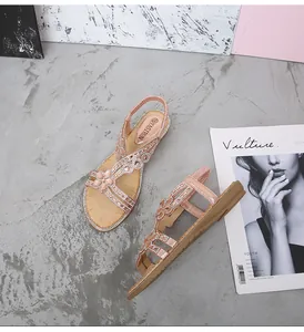 Détail de sandales plates or rose avec strass à motif floral et bride de talon élastique