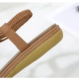 Detail of bohemian brown leather sandals featuring elastic heel strap and white stitching