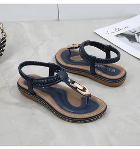 Detail of dark blue thong sandals with gold metal buckle and woven strap on marble surface