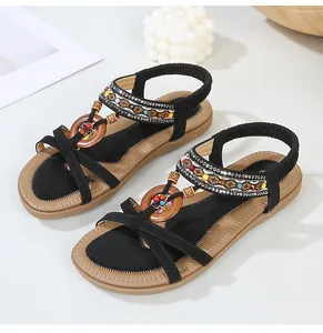 Detail of bohemian flat sandals featuring colorful beads, wooden rings and elastic straps