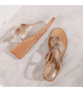 Dettaglio di sandali con zeppa oro champagne con decorazioni floreali in strass raffinati