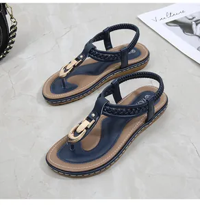 Detail of navy blue thong sandals with gold buckle and woven strap on marble surface