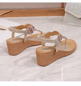 Dettaglio di sandali con zeppa oro champagne con fiori di strass e cinturino elastico