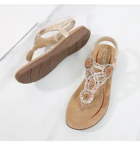 Λεπτομερής άποψη από μπεζ boho σανδάλια με κρυστάλλινα στρας και φλοράλ διακοσμητικά