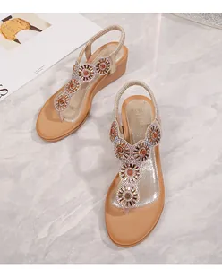 Dettaglio di sandali bohémien con zeppa con strass a girasole e cinturini in oro champagne