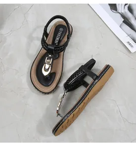 Close-up of black thong sandals with woven texture straps and gold horse-bit buckle detail