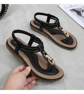 Detail of black thong sandals with gold buckle, woven texture, and elastic heel strap