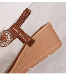 Dettaglio macro dei sandali con zeppa bohémien con strass e suola ondulata antiscivolo