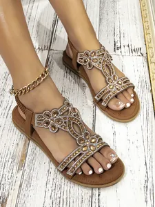Detail of brown bohemian flat sandals with hollow floral pattern and crystal rhinestones