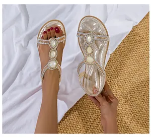 Detail von T-Riemchen-Sandalen mit großen weißen Schmucksteinen und funkelnden Strass