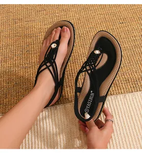 Gros plan sur les sandales tressées noires avec cristal sur un tapis de paille tressé