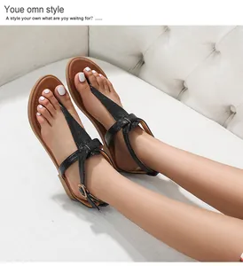 Close-up of black T-strap Roman sandals with crocodile texture and gold metal buckle